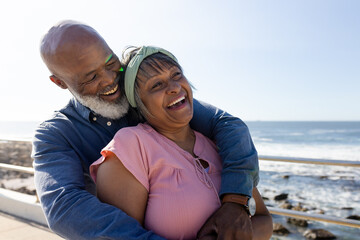 Happy senior african american couple embracing on promenade at seaside