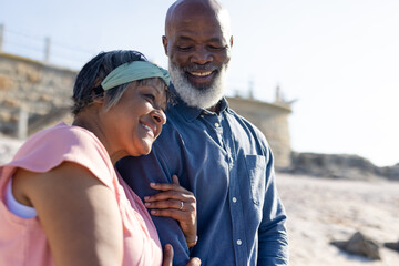 Happy senior african american couple embracing and admiring view at seaside