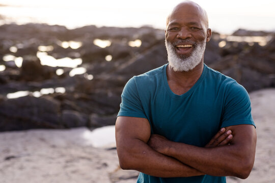 Portrait of happy senior african american man with arms crossed at beach