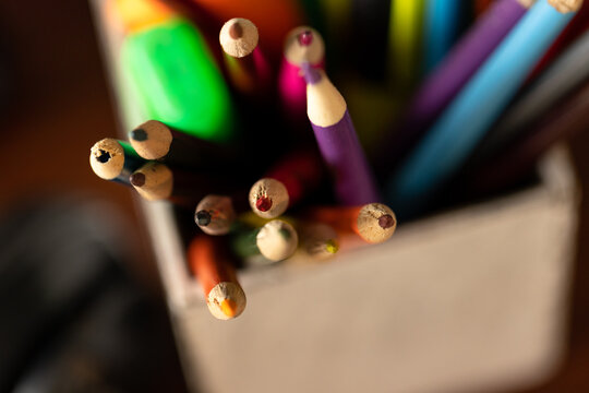 Coloured pencils and pens in pot on desk at home, selective focus