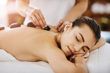 Obraz na płótnie Canvas Therapy, relax and woman getting a hot stone back massage at spa for luxury, calm and natural self care. Beauty, body care and tranquil female person sleeping while doing rock body treatment at salon