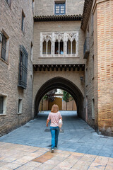 Fototapeta na wymiar Woman strolling among the beautiful medieval buildings of the old town of the city of Zaragoza, Spain.