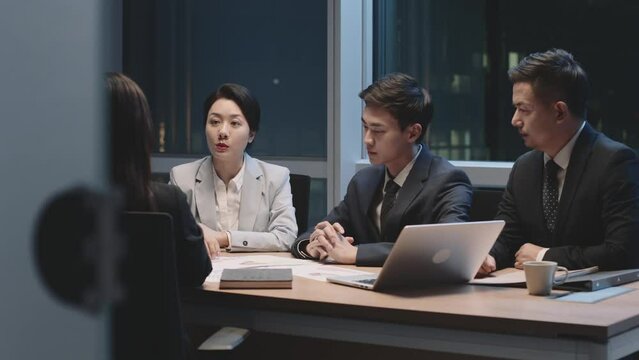 group of asian corporate executives working overtime meeting in office discussing business strategy