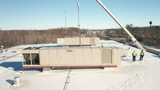 Aerial, workers installing new HVAC units onto industrial building roof top