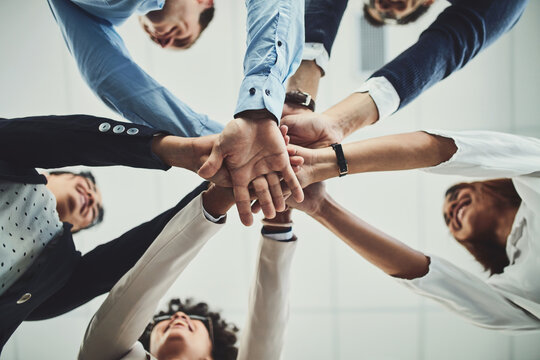 Hands together, business people and solidarity with low angle, support and team huddle with collaboration. Group of employees working in office, teamwork and mission with workforce and hand stack