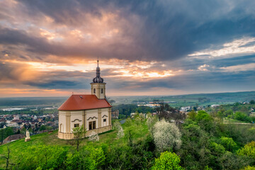 A holy Christian chapel on a hill at sunset. Beautiful dramatic sky full of clouds. 