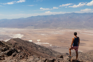 Fototapeta premium Rear view of man overlooking the Salt Badwater Basin and Panamint Mountains seen from Dante's View in Death Valley National Park, California, USA, America. Aerial scenic view on dry desert landscape