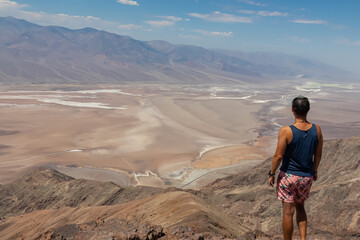 Fototapeta premium Rear view of man overlooking the Salt Badwater Basin and Panamint Mountains seen from Dante's View in Death Valley National Park, California, USA, America. Aerial scenic view on dry desert landscape