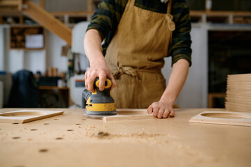 Closeup craftsman hands working with eccentric grinding machine