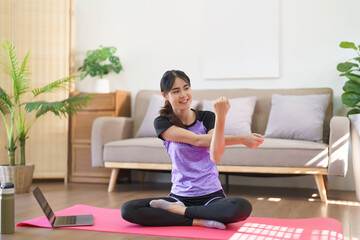 Fototapeta na wymiar Sporty woman watching yoga training online and doing stretching arms to exercise for yoga at home