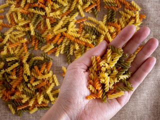 The hand of the cook keep in the palm of the Italian multicolored fusilli pasta