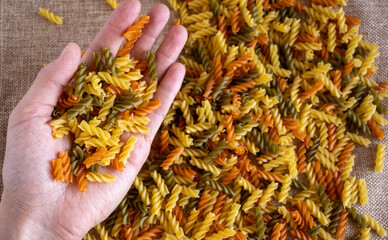 The hand of the cook keep in the palm of the Italian multicolored fusilli pasta