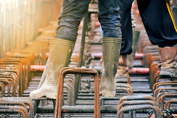 Construction worker pouring cement or concrete with pump tube at construction site
