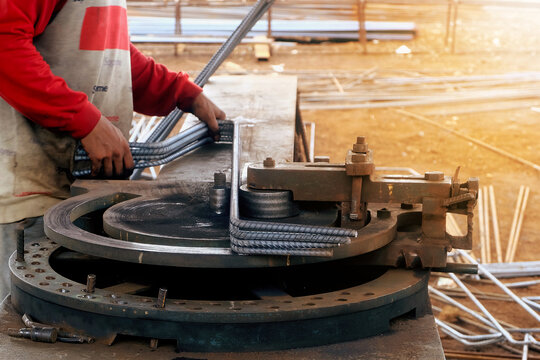 The worker is bending rebars with rebar bending machine in the site.