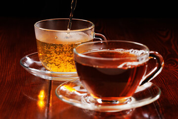 Green tea is poured into a glass cup. In the foreground is a cup of black tea. Selective focus on a cup of green tea.