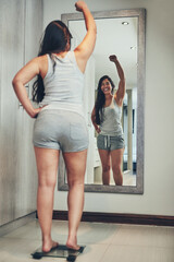 Celebration, weight loss goal and woman with scale and diet success in a home with mirror reflection. Cheering, happy and female person in a house with nutrition progress and a smile from wellness - obrazy, fototapety, plakaty
