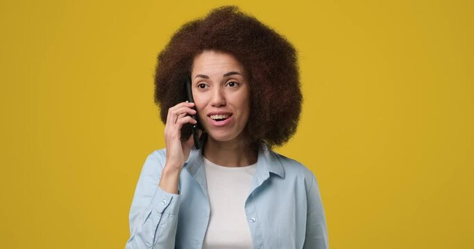 Young beautiful smiling African american woman talking on the phone answering phone call over yellow orange background