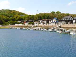 Fototapeta premium 日本の漁港全景。 住宅地区と堤防、係留されたボート。