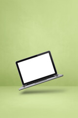 Floating computer laptop isolated on green. Vertical background