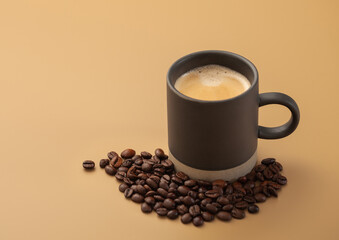 Coffee beans with cup of hot creamy black coffee on beige background.