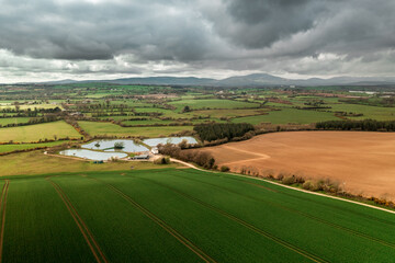 Irish countryside at sunset from a bird's-eye view, with three picturesque fishing lakes surrounded by lush agriculture land and rolling hills
