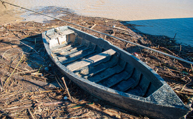 the old boat surrounded by debris carried by the swollen river