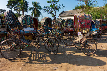 Fototapeta na wymiar Colorful rickshaws lined up on the unpaved ground.