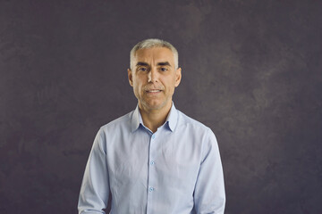 Headshot portrait of serious middle-aged Caucasian man isolated on black studio background. Profile picture of smiling confident successful mature male boss or businessman. Diversity, employment.