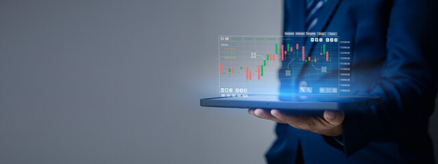 Businessman holding a device with a stock chart hologram, investing, using technology to invest in...