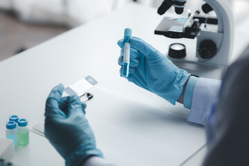 Lab assistant, medical scientist, chemistry researcher holds a glass tube through a chemical test tube, does a chemical experiment and examines a patient's sample. Medicine and research concept.