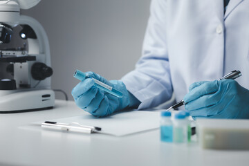 Lab assistant, medical scientist, chemistry researcher holds a glass tube through a chemical test tube, does a chemical experiment and examines a patient's sample. Medicine and research concept.