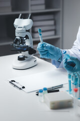 Fototapeta premium Lab assistant, medical scientist, chemistry researcher holds a glass tube through a chemical test tube, does a chemical experiment and examines a patient's sample. Medicine and research concept.
