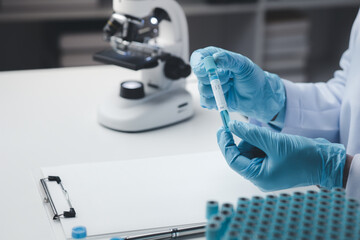 Lab assistant, medical scientist, chemistry researcher holds a glass tube through a chemical test tube, does a chemical experiment and examines a patient's sample. Medicine and research concept.
