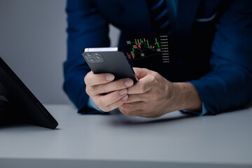 Businessman holding a device with a stock chart hologram, investing, using technology to invest in stocks. The concept of using technology in trading and analyzing stocks.