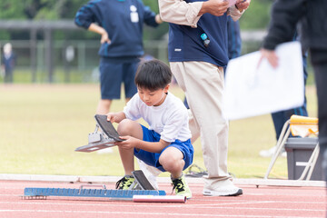 陸上競技大会でスタートの準備をする小学生の男の子