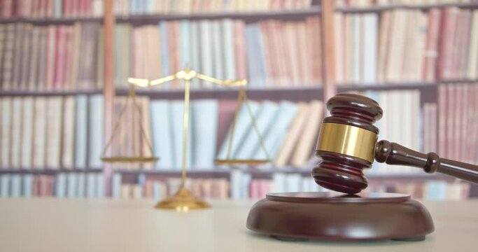 Legal office of lawyers, justice and law concept : Judge's gavel or hammer and base used by a judge person on a desk in a courtroom with balance scale of justice and blurred books in the background.
