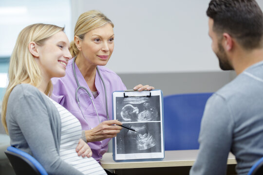 doctor showing happy couple pregnancy ultrasound picture