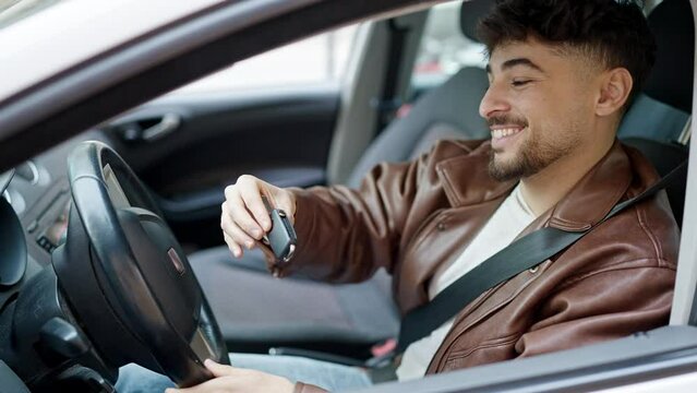 Young arab man smiling confident holding key of new car at street