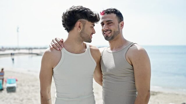 Two men couple smiling confident hugging each other at beach