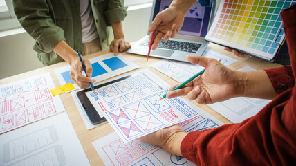 Close-up ux developers and ui designers use augmented reality to brainstorm on mobile app interface wireframe designs on modern office desks. Creative digital development office