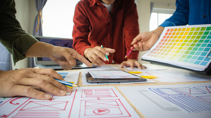 Close-up ux developers and ui designers use augmented reality to brainstorm on mobile app interface wireframe designs on modern office desks. Creative digital development office