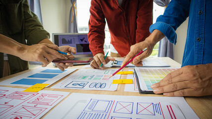 Fototapeta premium Close-up ux developers and ui designers use augmented reality to brainstorm on mobile app interface wireframe designs on modern office desks. Creative digital development office