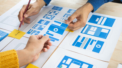 Close-up ux developers and ui designers use augmented reality to brainstorm on mobile app interface...
