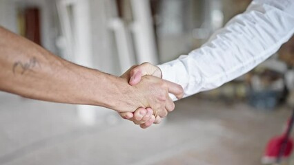 Two men shake hands at construction site