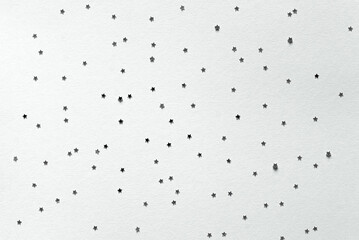 Holiday greeting card.	Christmas, New Year party mockup scene with silver star shape glittering confetti and empty space. Gray paper background.