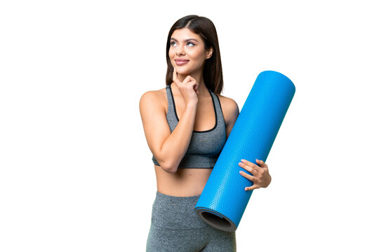 Young sport woman going to yoga classes while holding a mat over isolated chroma key background thinking an idea while looking up