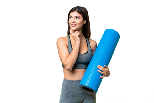 Young sport woman going to yoga classes while holding a mat over isolated chroma key background thinking an idea while looking up