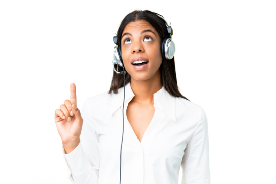 Telemarketer African American woman working with a headset over isolated chroma key background pointing up and surprised