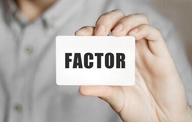 Card with text Factor in a man's hand