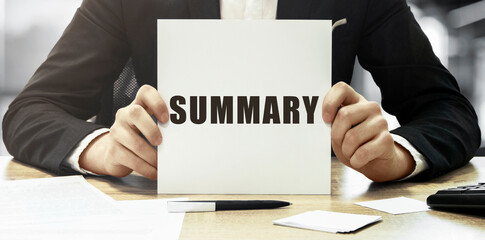 Businessman holding a white card with text Summary on office background